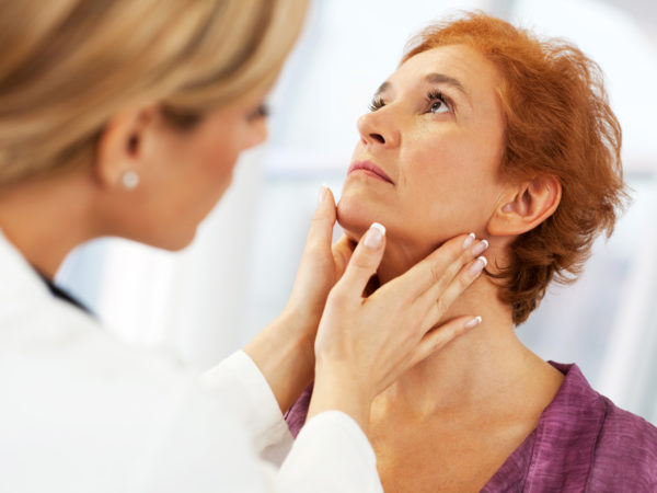 Close-up of a female doctor doing a medical examination. The focus is on the mature adult woman being examined.