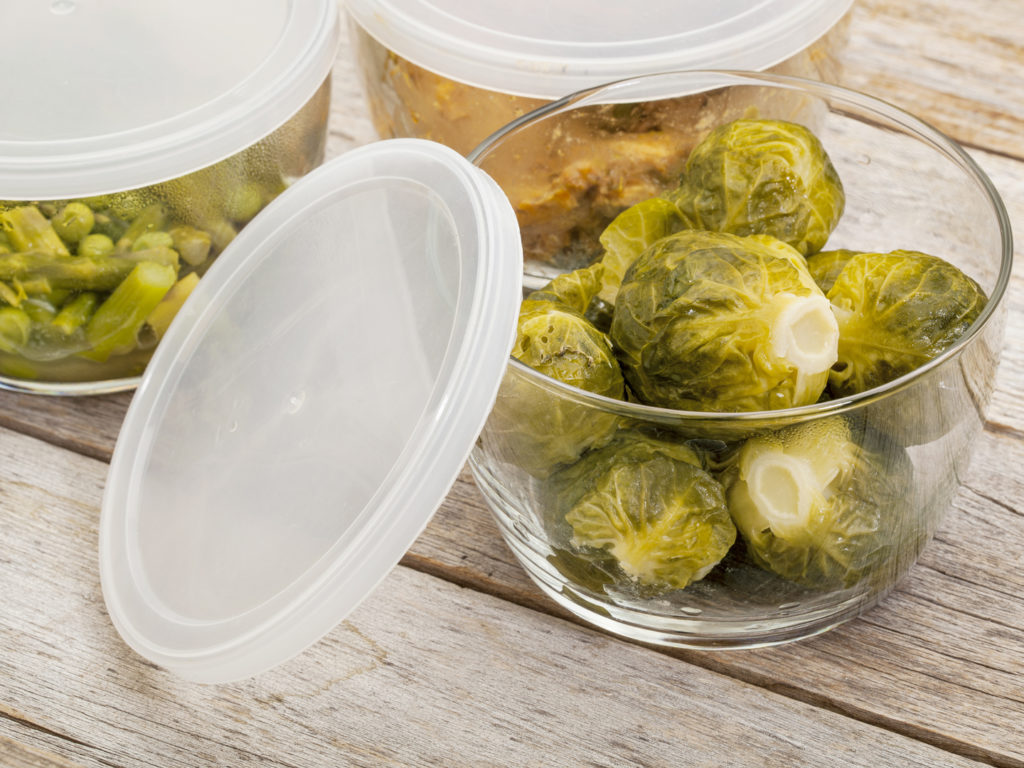 dinner meal or leftovers (chicken, brussels sprouts, asparagus, green pea) stored in glass containers