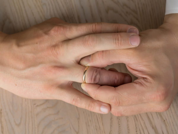 Divorce, separation: hands of married man removing wedding or engagement ring