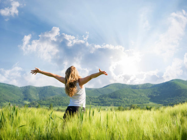 young woman with hands outstretched in the field