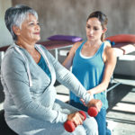 Shot of a senior woman using weights and a fitness ball with the help of a physical therapist