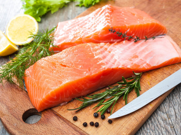 Raw salmon fish fillet with fresh herbs on cutting board