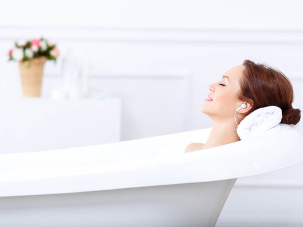 Just relax. Content beautiful young woman listening to music and closing her eyes while taking a bath