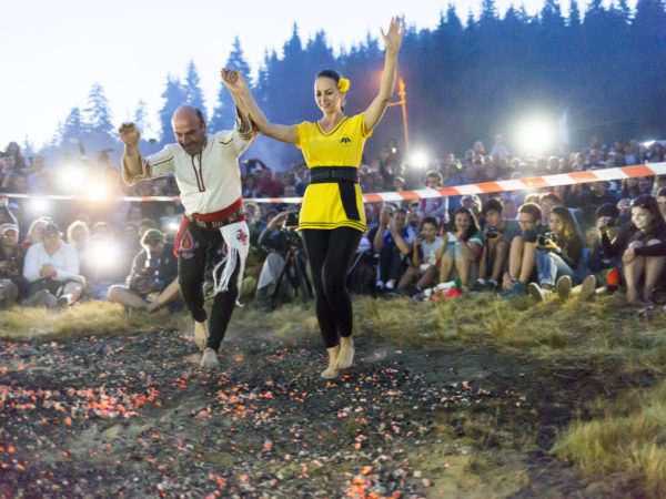 Rozhen, Bulgaria - July 18, 2015: A nestinar man and woman are walking on fire during a nestinarstvo show. The fire ritual involves a barefoot dance on smouldering embers performed by nestinari.