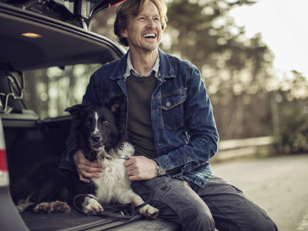 Photo of a man sitting in the car and cuddle his dog