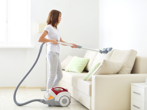 Attractive girl with vacuum cleaner on light background