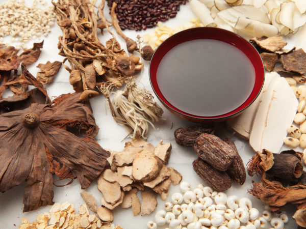 Subject: A variety of Chinese herbal medicine ingredients and the resulting tonic tea displayed on a marble board.