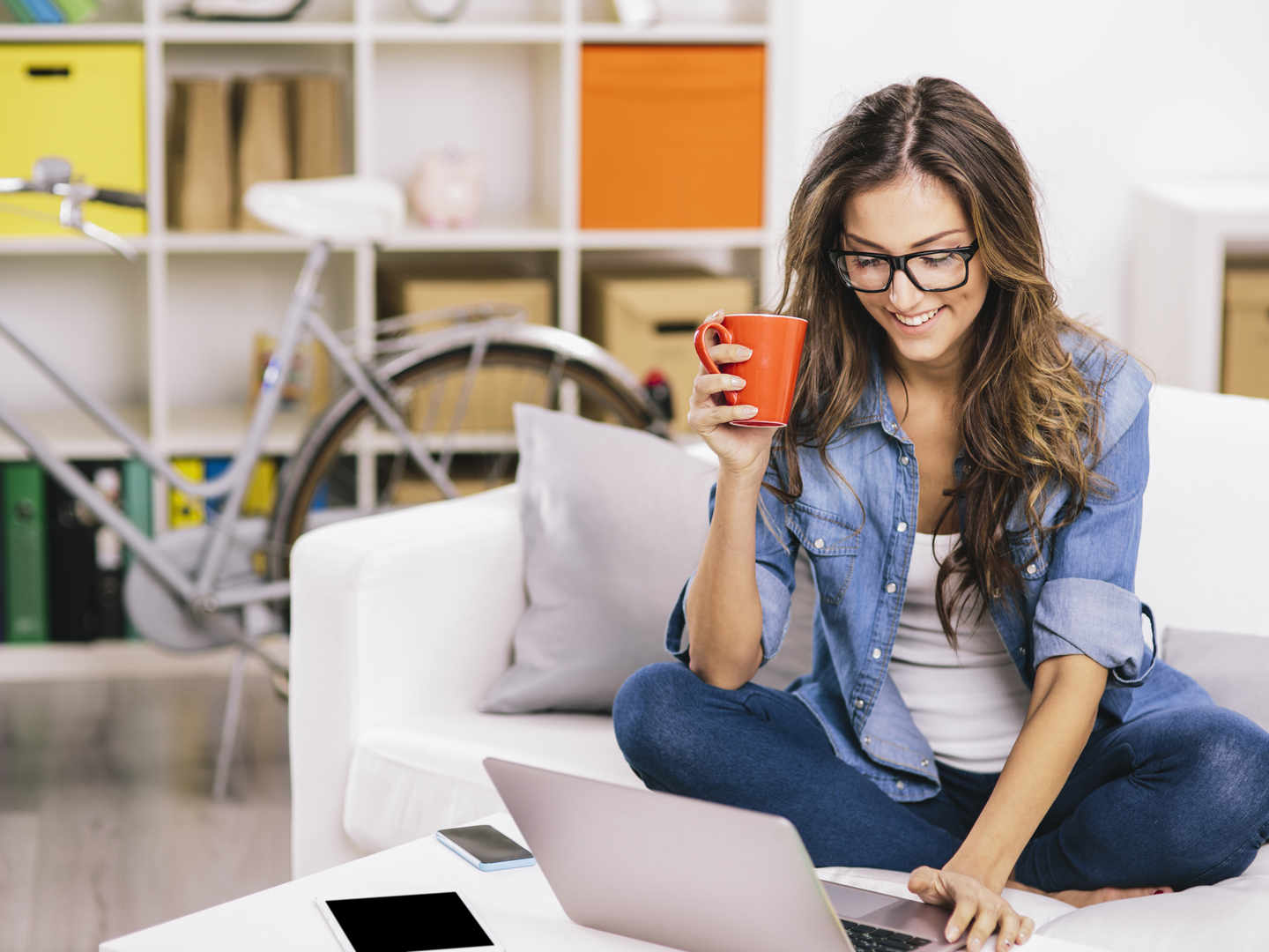 Woman sitting on a sofa and using a laptop.