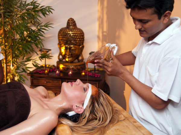Indian massage therapist doing a Ayurveda massage with aromatic oils.