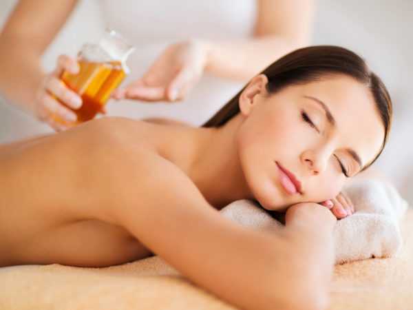 beauty, people, body care and relaxation concept - beautiful woman in spa salon having oil massage