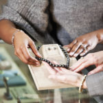 Hands of saleswoman helping customer look at merchandise in jewelry store.