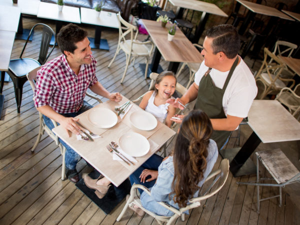 Waiter serving a happy Latin American family having dinner at a restaurant