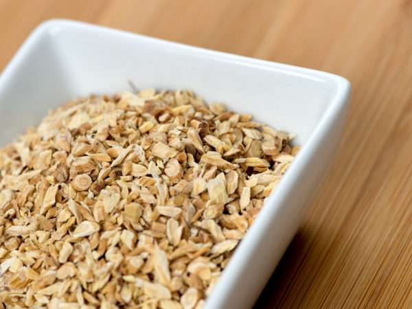 Macro of astragalus root chips against a wooden board