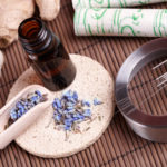Acupuncture needles laying on the stone mat, moxa sticks on wooden desk and lavender petals with macerated oil. TCM Traditional Chinese Medicine concept photo