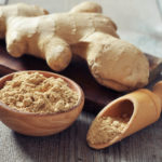 Fresh ginger root and ground ginger spice on wooden background