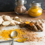 Healthy living begins with healthy food. Turmeric root and ginger root may help with anti-aging. Add to food, use as a tonic, or display a healthy lifestyle. Black background, classic spice jars, and ground curcumin and ginger with spoons