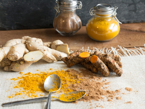 Healthy living begins with healthy food. Turmeric root and ginger root may help with anti-aging. Add to food, use as a tonic, or display a healthy lifestyle. Black background, classic spice jars, and ground curcumin and ginger with spoons