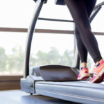 Woman training hard on treadmill, low section, focus on sports shoes