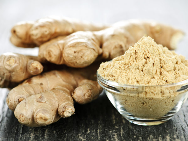 Fresh and ground ginger root spice on wooden table