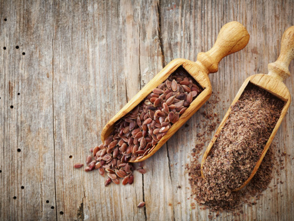 whole and crushed flax seeds on old wooden table