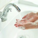 Man washing his hands under running water.