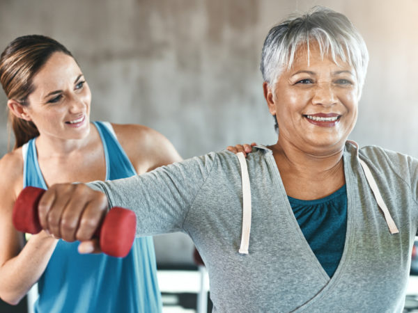 Shot of a senior woman using weights with the help of a physical therapist