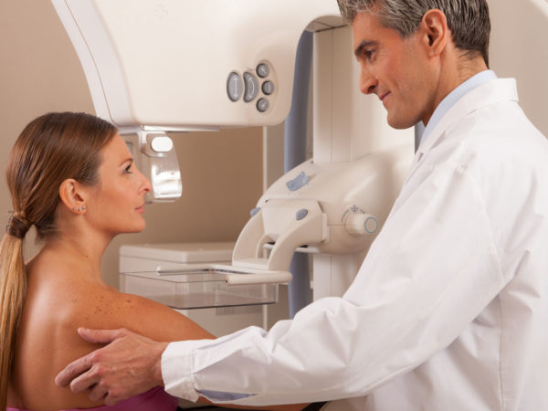 Young male doctor reassuring woman before mammography scan.