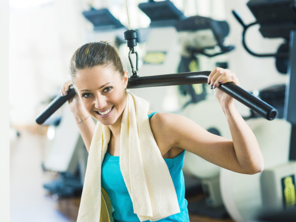 Attractive woman exercising at gym, biceps workout on a machine.