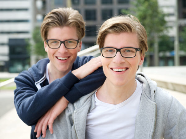 Close up portrait of two brothers with glasses smiling outdoors
