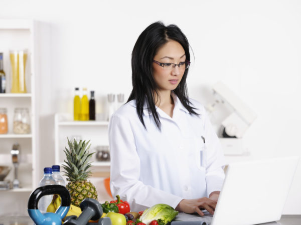 A portrait of an oriental healthcare professional reviewing something on a laptop.