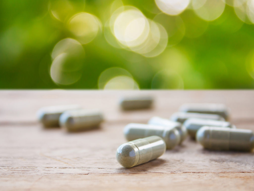 Herbal capsules on wooden table