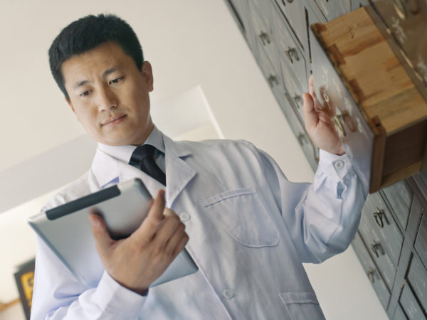 Traditional Chinese doctor looking at tablet computer