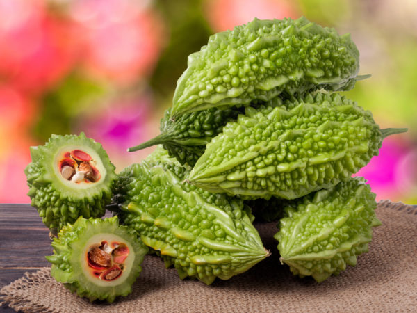 heap of bitter melon or momordica on wooden table with blurred background.