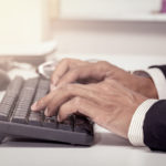 Businessman hand typing on keyboard and working in office in vintage color filter
