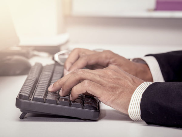 Businessman hand typing on keyboard and working in office in vintage color filter