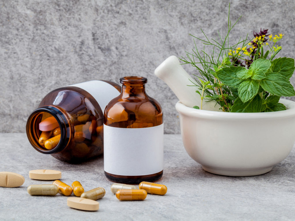 Alternative health care fresh herbs rosemary ,lemon thyme ,fennel ,peppermint ,basil flower and herbal capsule with mortar on stone background.