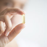 Woman holding omega 3 capsule.