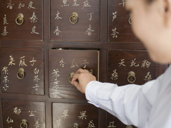 Traditional Chinese doctor opening medicine cabinet drawer