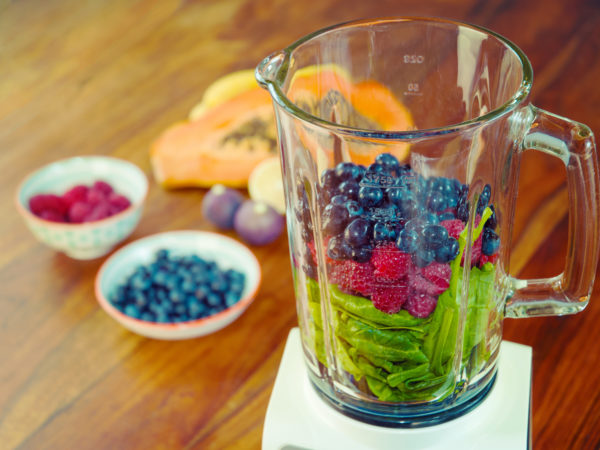 Fruits and vegetables as ingredients for a healthy smoothie: papaya, figs, lemon, blueberries, pomegranate seeds, raspberries and baby spinach