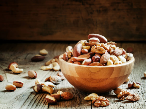 Nuts set in bowl almonds, pistachios, cashews, hazelnuts, peanuts, Brazil nuts, walnuts, vintage wooden background, focus vyboronchy
