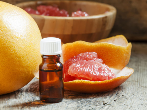 Grapefruit essential oil in a small bottle and fresh grapefruit, selective focus