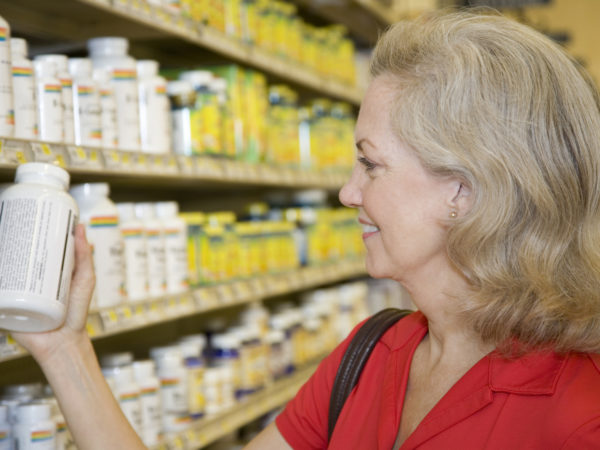 Senior Adult Female Reading Contents of Vitamin Bottle.