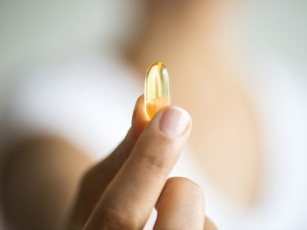 Woman holding omega 3 capsule.