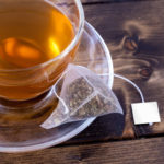 Green tea in a glass teacup on a rustic wooden table