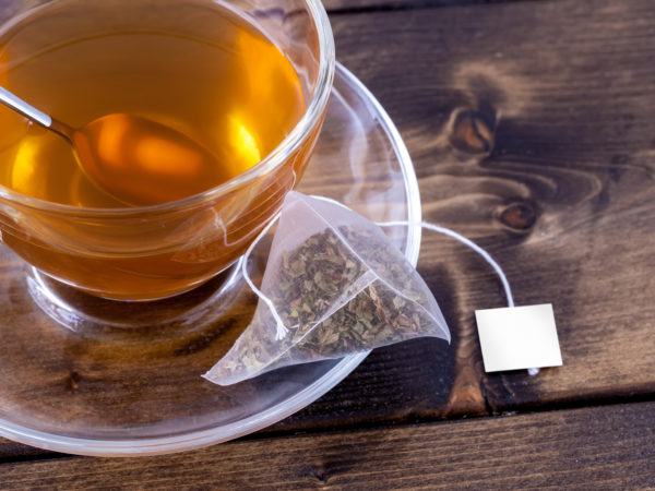 Green tea in a glass teacup on a rustic wooden table