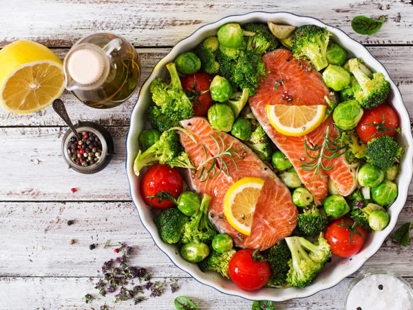 Raw salmon steak and vegetables for cooking on a light wooden background in a rustic style. Top view