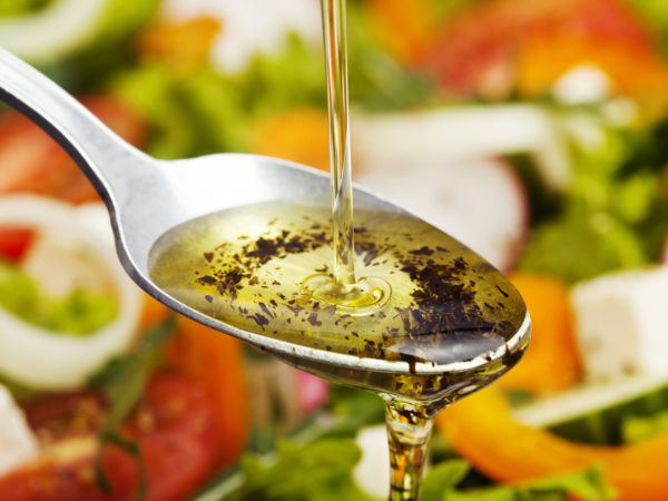 Olive oil pouring over salad.