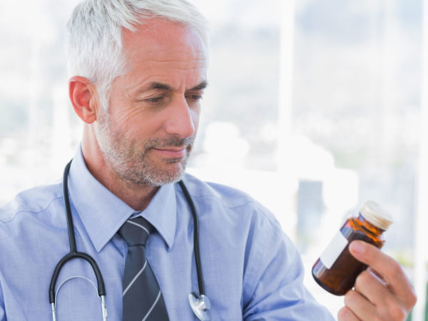 Attractive doctor looking at medicine jar