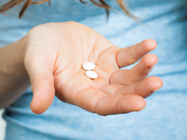 Close-up shot of a hand holding two white pills.