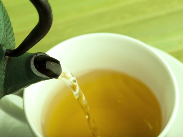 Green tea is poured from the cast-iron pot into a bowl.